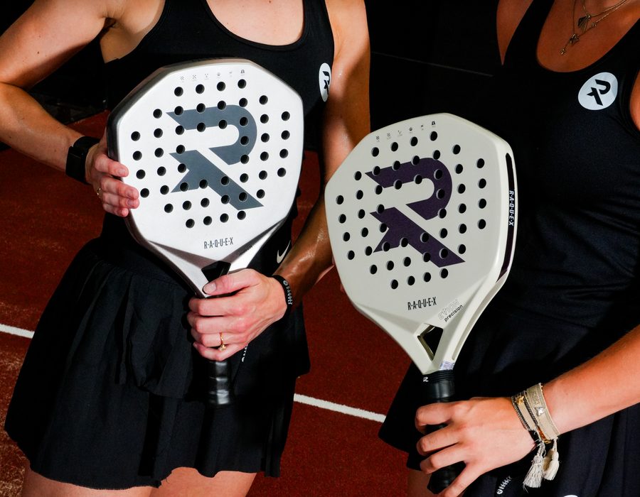 Two players in black Raquex kit holding white and cream Raquex padel racquets