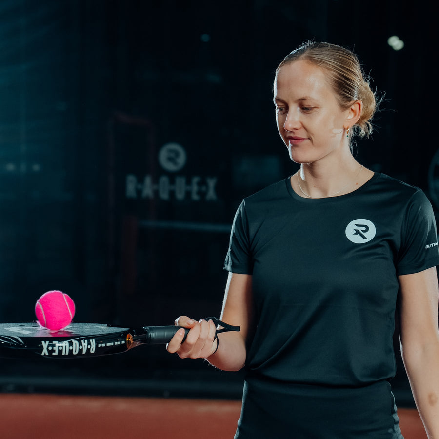 A pink Raquex Elite padel ball balanced on the face of a Raquex racquet