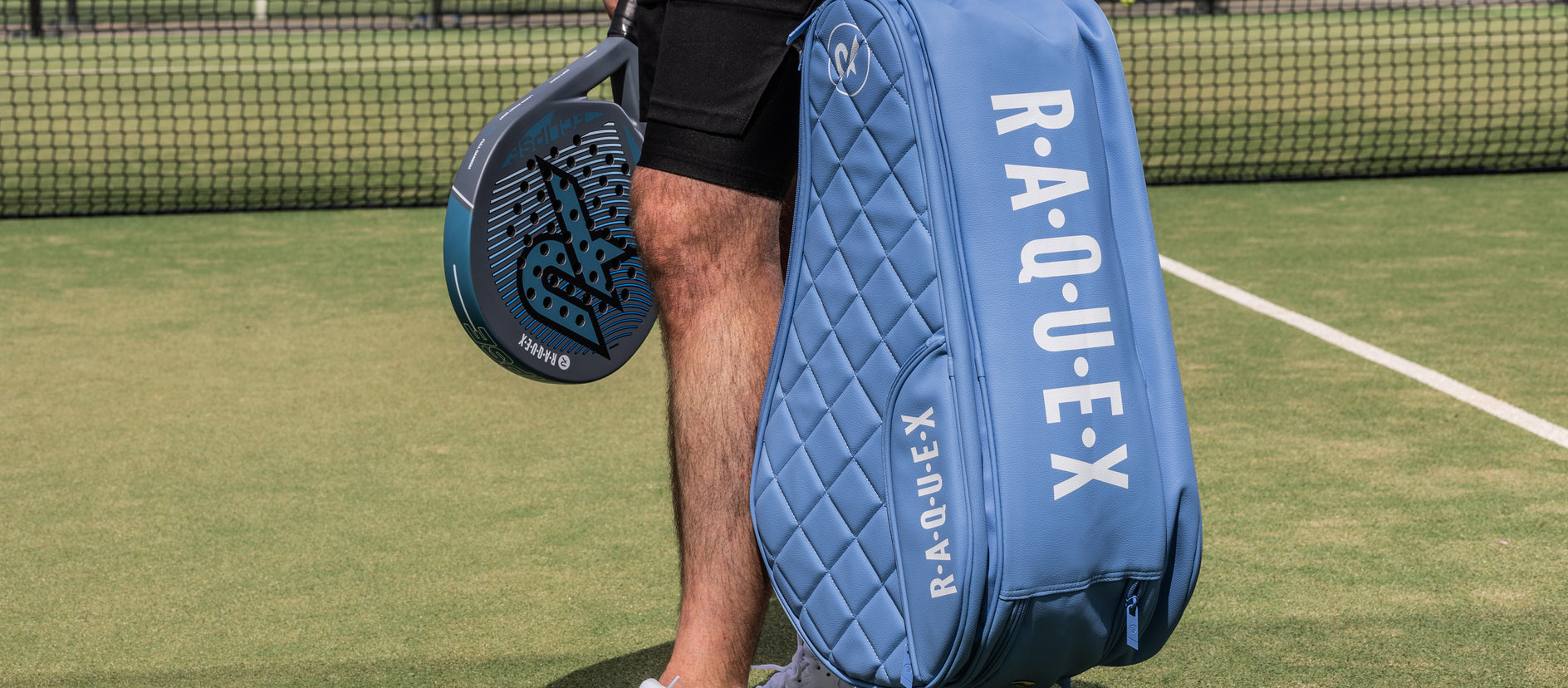 A man holding a Raquex padel bag on a court.