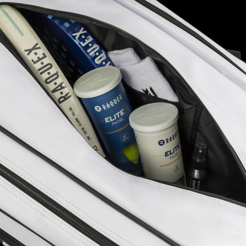 Close-up inside the white Raquex Execute Tour padel bag with padel racquets and Raquex Elite ball tubes