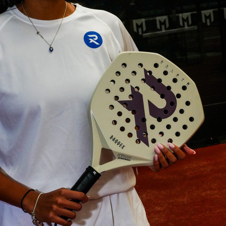 Cream Raquex padel racquet held up close, showing its textured face and purple R logo