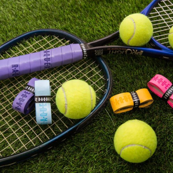 Tennis racquet with purple grip tape and tennis balls, with various colours of replacement racquet tape on a grass background