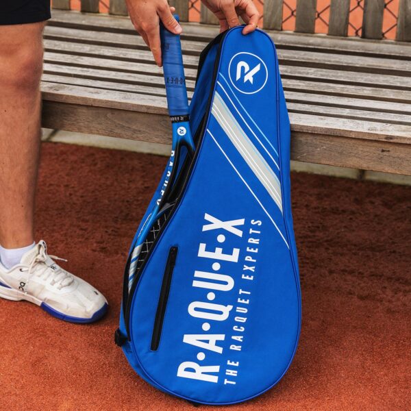 Tennis racquet cover in blue and black and matching racquet next to a wooden bench on a tennis court