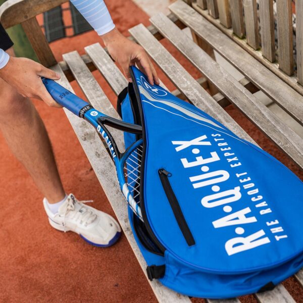 Tennis racquet cover in blue and black and matching racquet on wooden bench on a tennis court